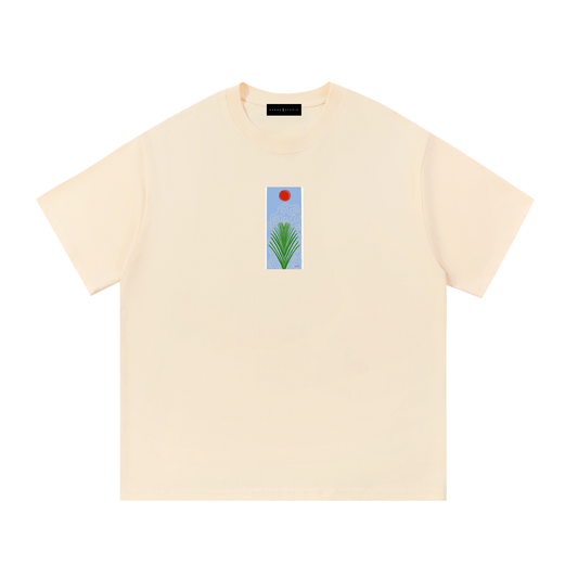 A cream-colored short-sleeve t-shirt with a small vertical graphic print on the center chest showing a green palm frond against a light blue background with a red sun, displayed on a solid white background.
